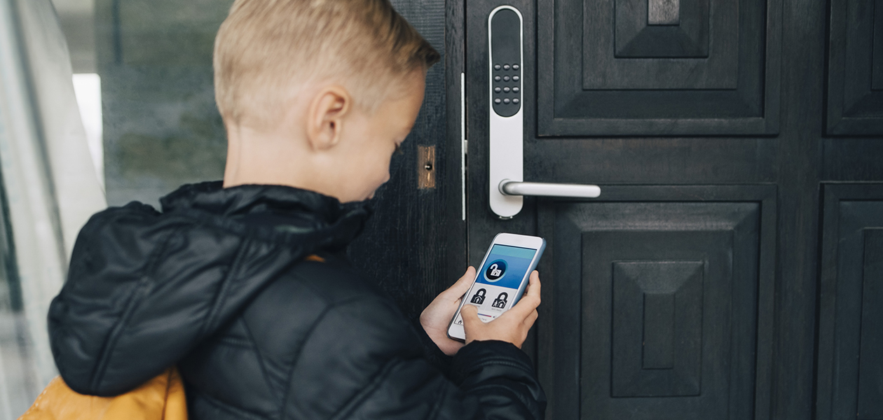 Smart lås kan till och med ibland installeras i äldre dörrar. En kille låser upp ett smartlås med en smartphone-app.