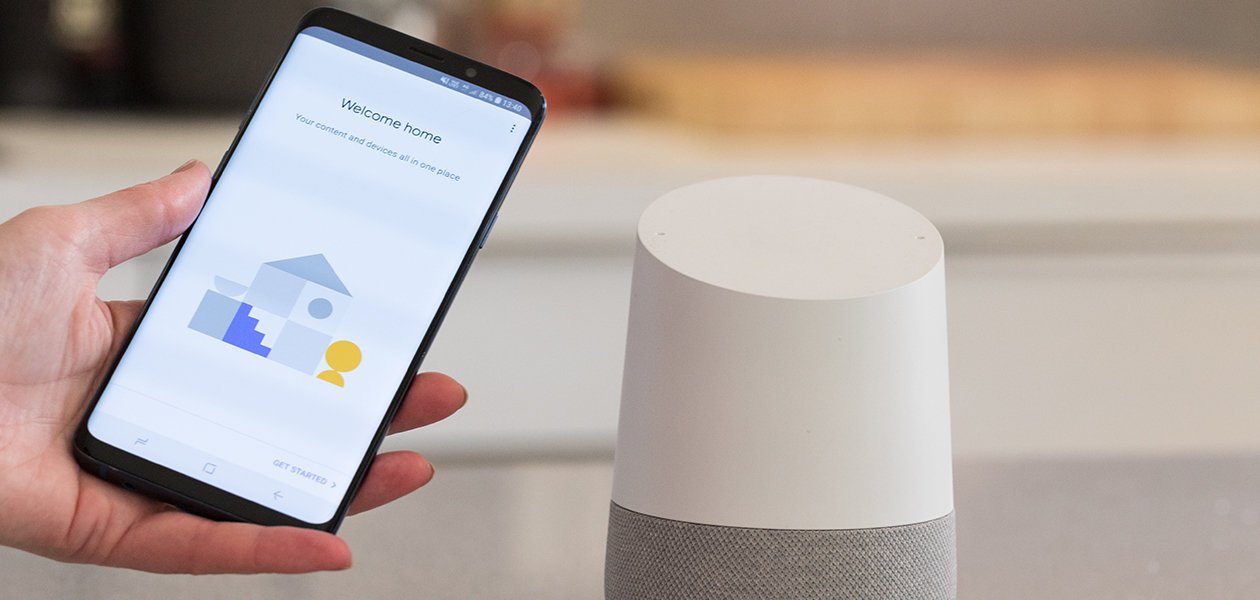 Så får du tillgång till din kalender från din Google Home En hand som håller en smartphone bredvid en Google Home-högtalare
