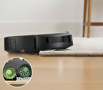 Bild på en Roomba i7+ som dammsuger en matta Närbild på två Multi-Surface dammuppsamlare och Roomba i7 i bakgrunden