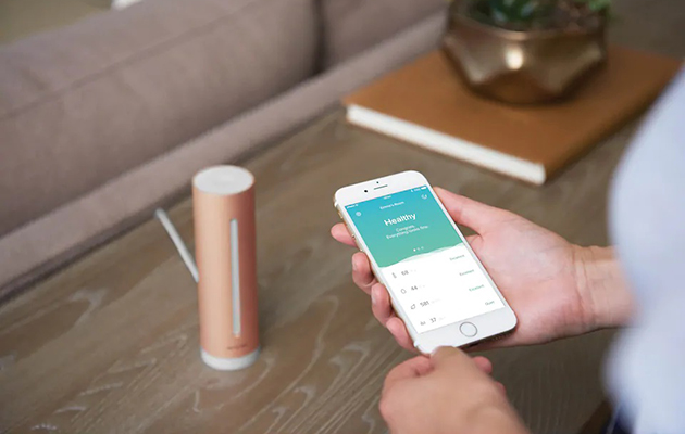 Så börjar du förbättra din hemmilljö Händer som håller en mobiltelefon med en smart-app på skärmen
