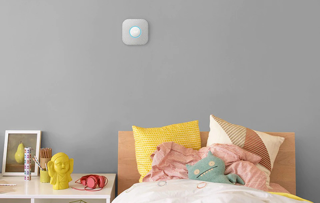Skapa kedjekopplingar mellan olika enheter och appar En Nest Protect brandvarnare fäst på en vägg över en säng