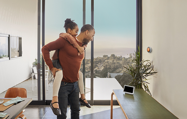 Google Nest Hub smälter perfekt in i hemmet Barn som sitter på sin pappas rygg och båda tittar på Google Nest Hub