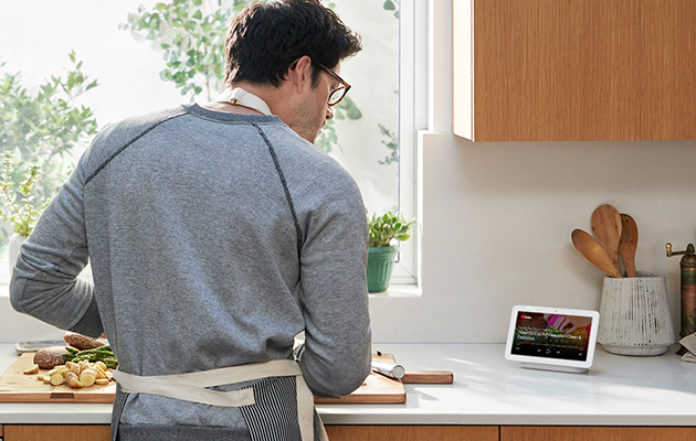 Spela upp videor och låtar från YouTube Man som står i köket, får hjälp med matlagningen, och tittar på YouTube video på Google Nest Hub