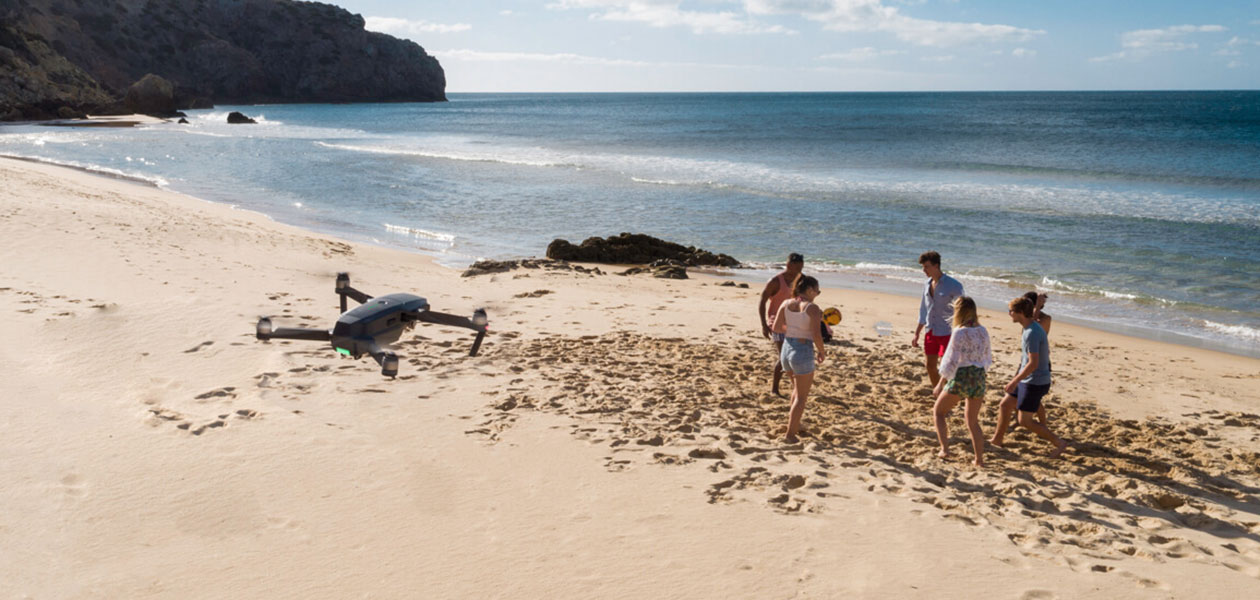 Se världen från ett nytt perspektiv Drönare flyger över en strand med folk som leker en bit bort