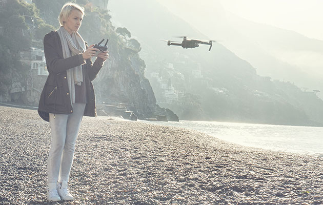 Världen från ett nytt perspektiv Kvinna flyger drönare över en strand