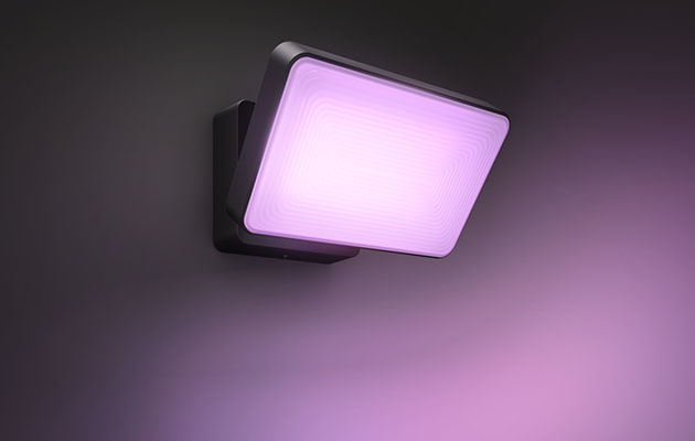 En Hue Discover lampa som ger ifrån sig lila ljus och sitter på väggen