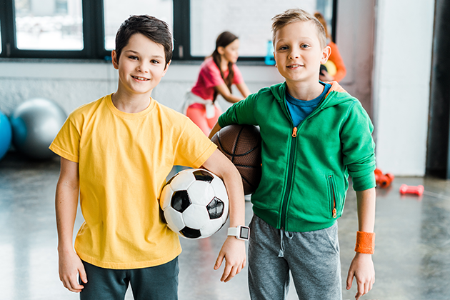 Välj rätt träningsklocka till ditt barn Två killar i en gymnastiksal med boll. Den ena killen har en träningsklocka.