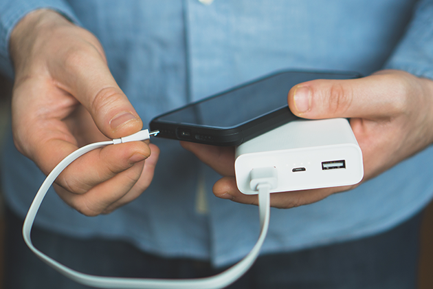 Du kan enkelt ladda din mobiltelefon med en powerbank Person som håller mobiltelefon och powerbank