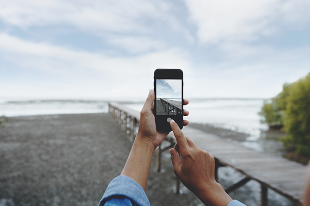 Få tips på hur du tar bättre bilder Person tar bilder av strand med sin mobiltelefon
