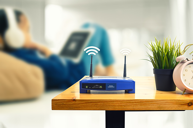 Placera routern på en central plats En router på ett bord och en person i bakgrunden