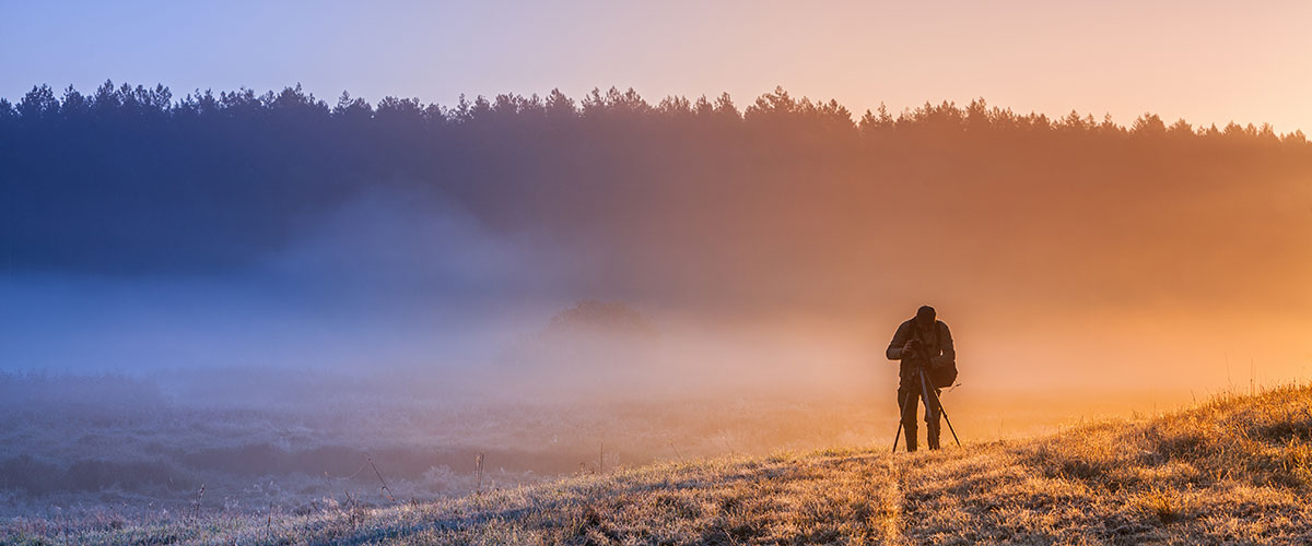 Månadens fotodeal En dimmig jord med frost på marken och silhuetten av en fotograf, ljuset är varmt
