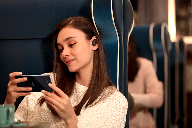 Sony Xperia 5 har Dolby Atmos ljud Kvinna sitter på toget med Sony Xperia 5 och hörlurar