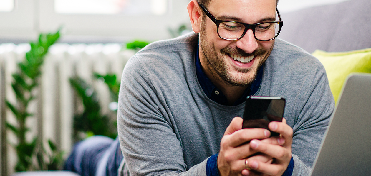Vi gör det lättare att byta mobiltelefon En man som ler och kollar på sin mobiltelefon