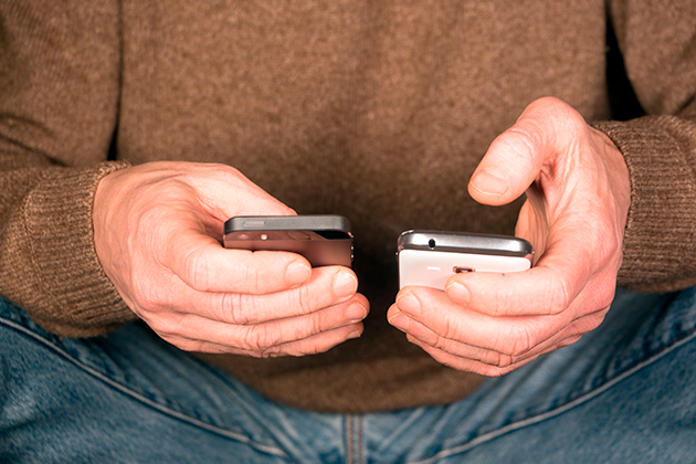 Hur jämför jag olika modeller? Man som håller två mobiltelefoner i handen