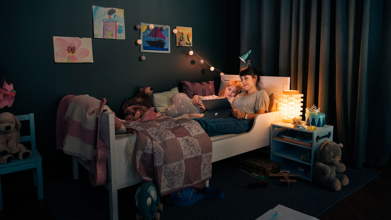 Surface Pro 7 ägnar sig för både jobb och fritid En kvinna och hennes dotter i en säng med Surface Pro 7