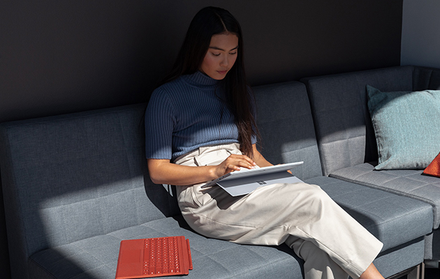 Använd Surface Pro 7 på ditt sätt Kvinna som sitter i en soffa och använder Surface Pro 7