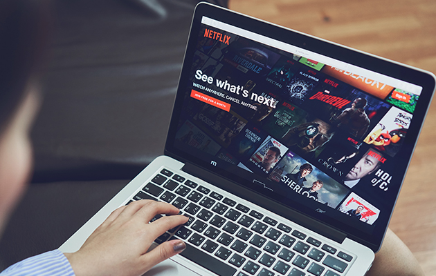 TV eller bärbar dator? En person som sitter i en soffa med en dator och tittar på Netflix