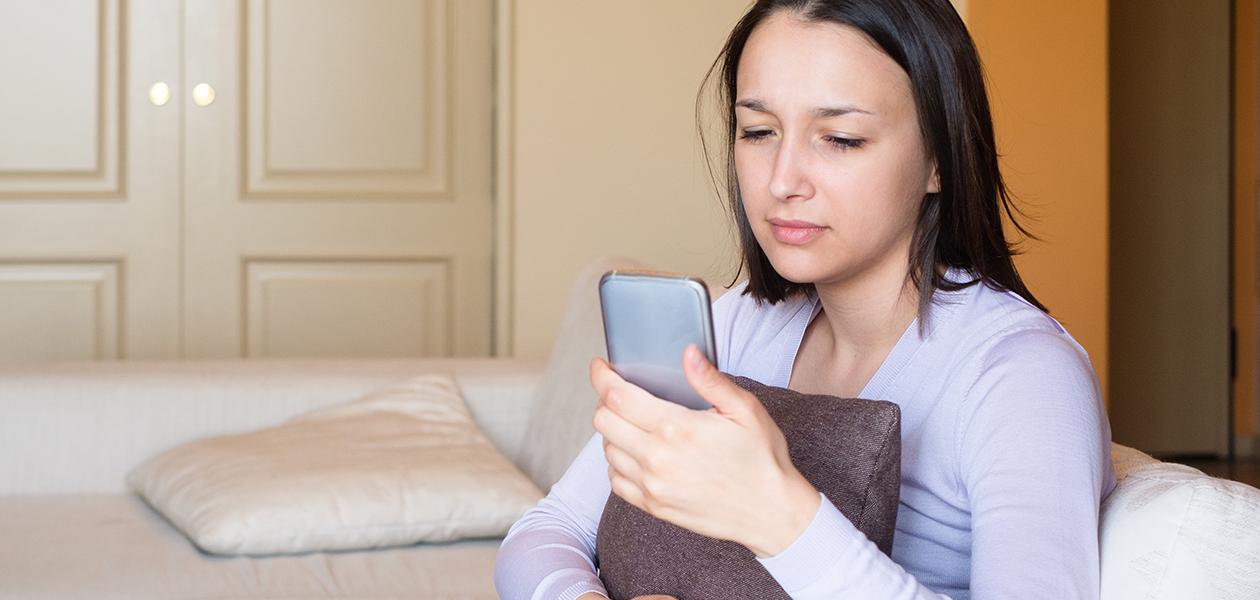 Skydda din mobiltelefon mot virus och malware En ledsen kvinna tittar på sin mobiltelefon