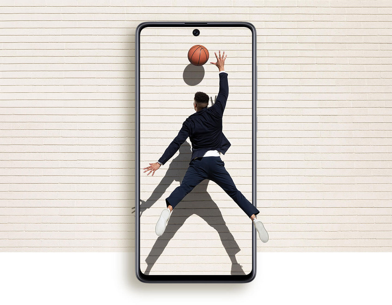 Upplev mer med en större skärm Förstorad Samsung Galaxy A71 mobiltelefon och man som sträcker ut armen efter en basketboll
