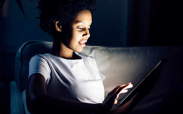 Huawei MediaPad T5 skyddar dina ögon Kvinna sitter i mörkret med en Huawei MediaPad T5 surfplatta