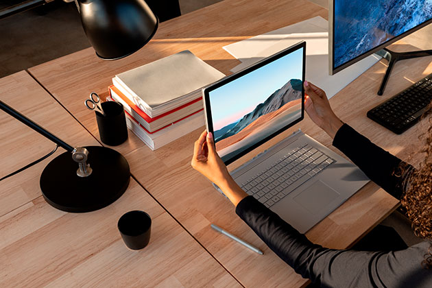 Surface Book 3 är lika dynamisk som dig Kvinna med Surface Book 3 på ett bord