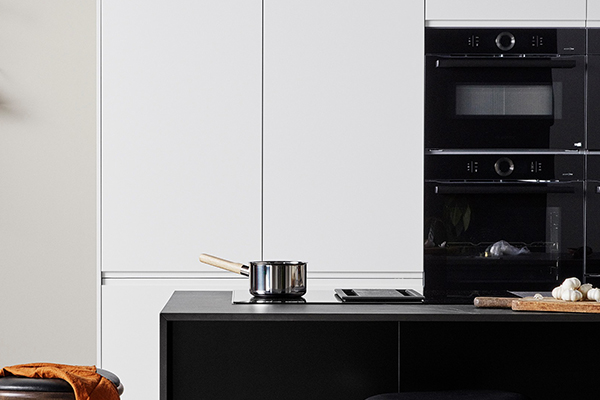 Häll med inbyggd fläkt - design möter funktion En svart köksö med en induktionshäll med inbyggd fläkt