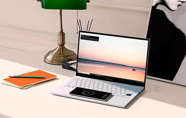 Du kan ladda din telefon direkt på Samsung Galaxy Book Ions touchpad Smartphone som ligger på en Samsung Galaxy Book Ion och laddar