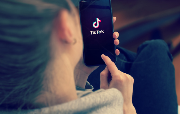 Hur blir man populär på TikTok? En hand med en telefon med TikTok på skärmen