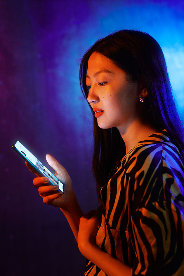 Upplev mer på den stora AMOLED-skärmen OnePlus Nord med lysande skärm i handen på en kvinna i ett neonbelyst rum