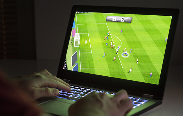Bakgrundsbelyst tangentbord Person spelar fotbollsspel på bärbar dator