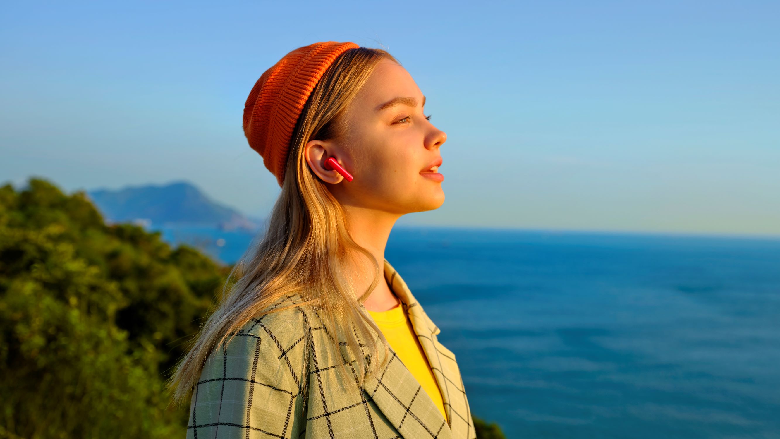 Huawei Freebuds 4i minskar ljudet av vind Kvinna med Huawei Freebuds 4i som ser ut över havet