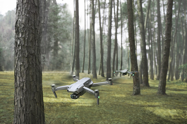 Två DJI Air 2S flyger efter varandra i en skog