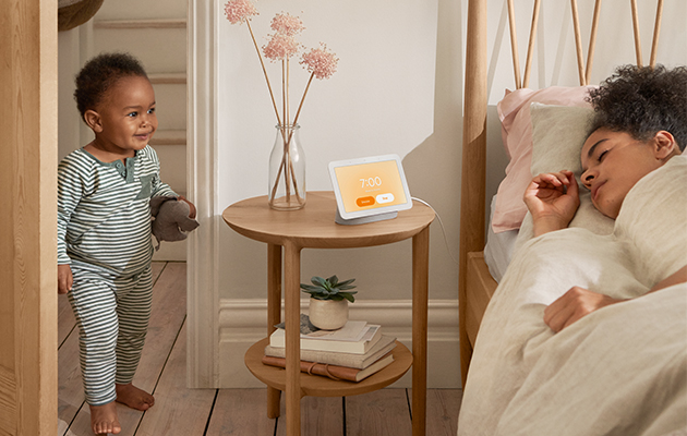 Med Nest Hub på nattduksbordet blir det enklare att somna och vakna Pojke som går in i ett rum där en kvinna sover med Google Nest Hub på nattduksbordet
