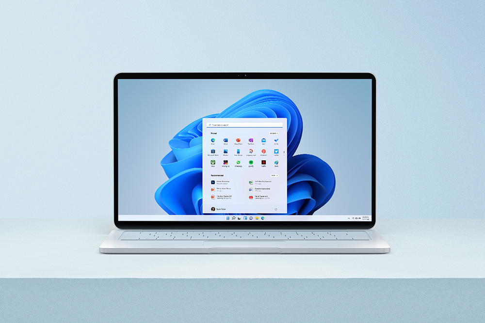 Windows 11 Windows 11-dator står på ett vitt bord med hemskärmen öppen på datorn