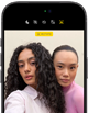 iPhone 18 Pro, i färgen svart, sedd framifrån, två modeller som poserar framför kameran för att visa Center Stage-skärmkameran