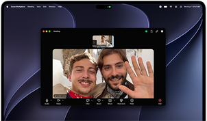 MacBook Pro med PROLED XDR-skärm, silver, skärmen visar ett pågående videosamtal med två personer i en stad med vackert solsken som vinkar till en person hemma
