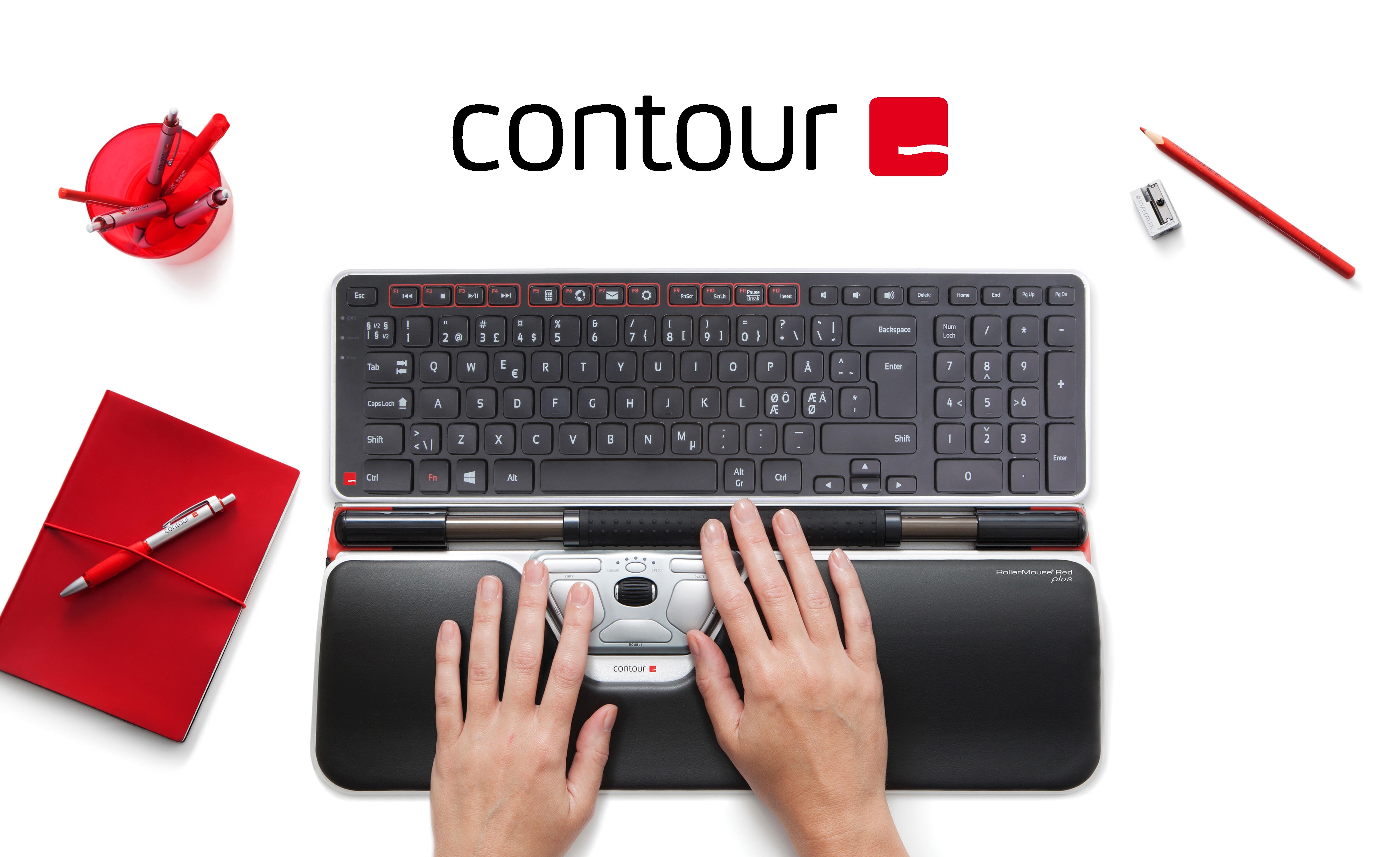 Contour tillbehör på ett vitt bord, intill en datorskärm och röd kontorsutrustning