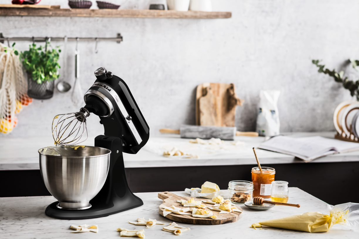 Svart köksmaskin från KitchenAid på en köksö med massa frukostgrejer på.