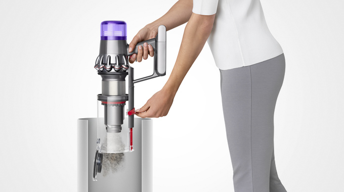 Kvinna som visar hur lätt det är att tömma en Dyson V11-dammsugare.