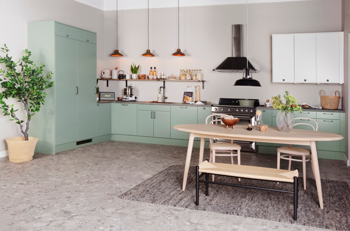 A light green kitchen with white oak details
