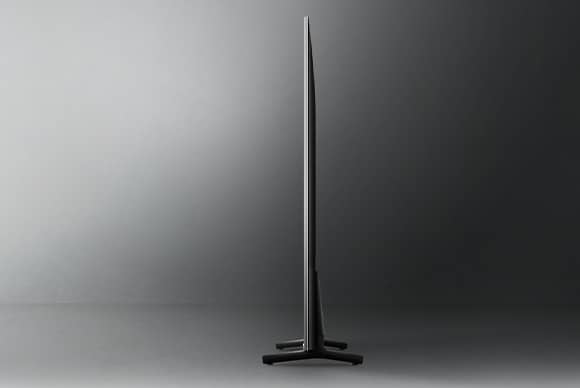 Samsung TV på stativ  i profil för att visa hur tunn den är, svart bakgrund. 