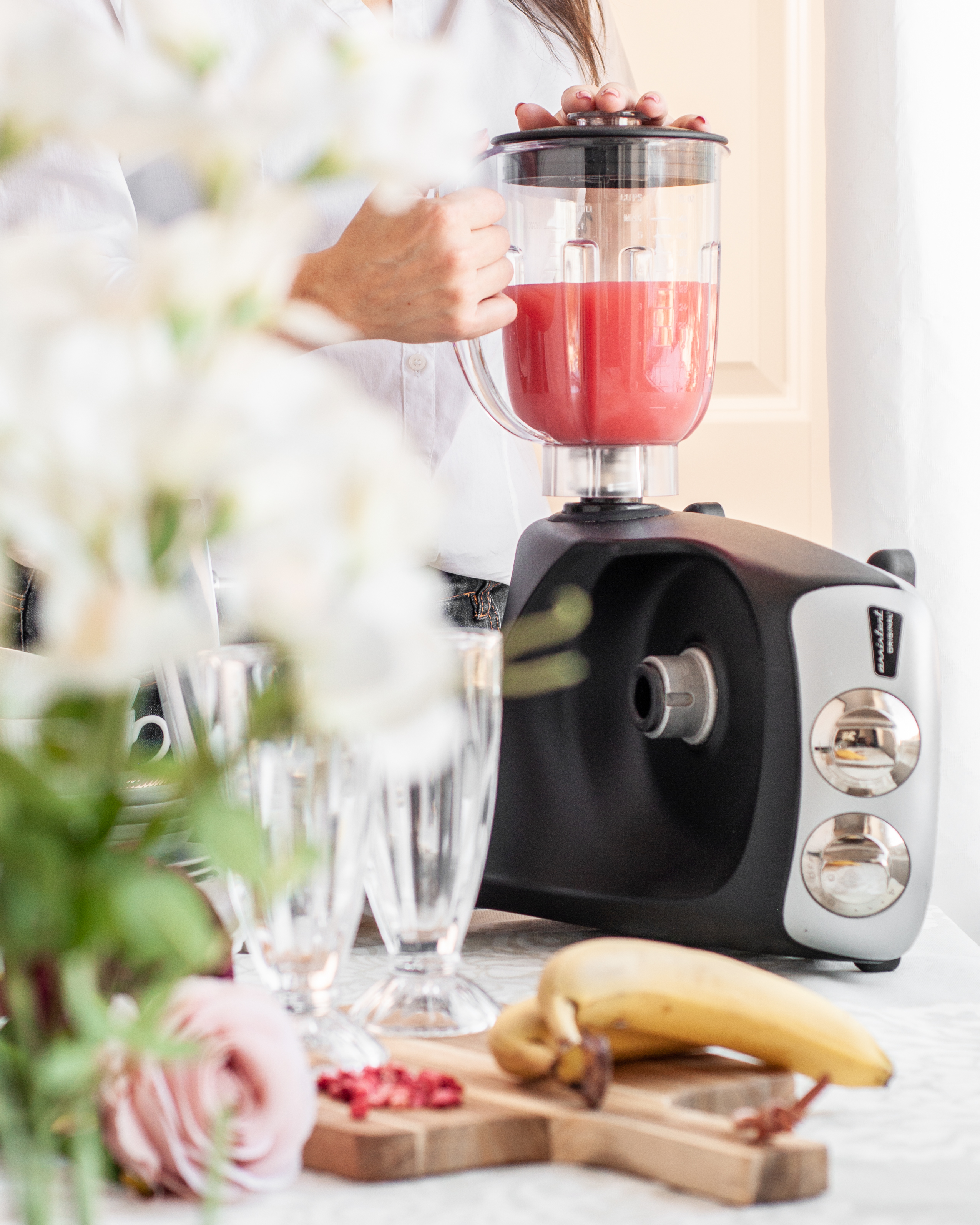 En kvinna håller en Ankarsum Assistant-blender som innehåller rosa juice på en köksbänk