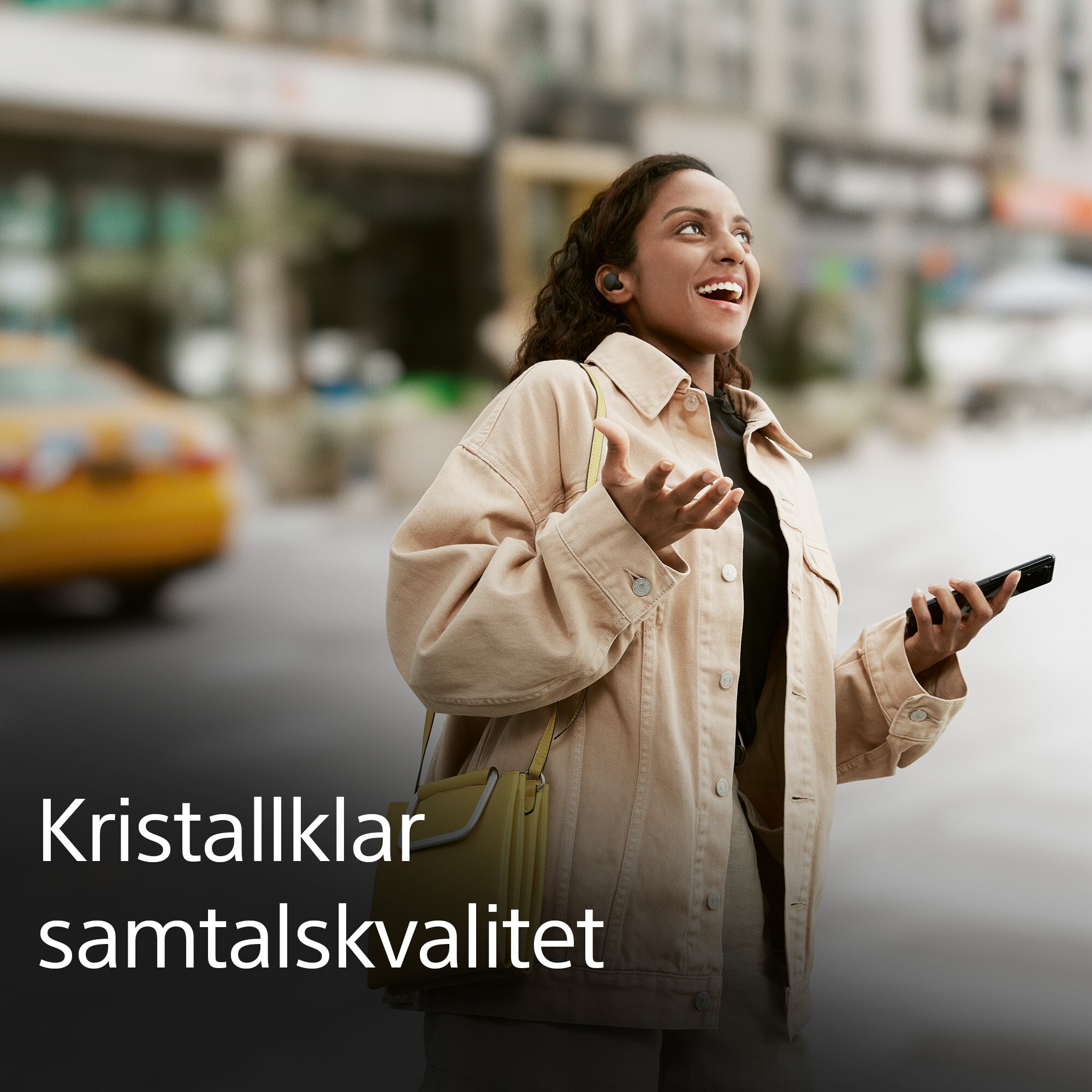 Glad kvinna med LinkBuds på en gata i en stad som pratar engagerat med någon i telefonen och svensk, vit text om samtalskvalitet