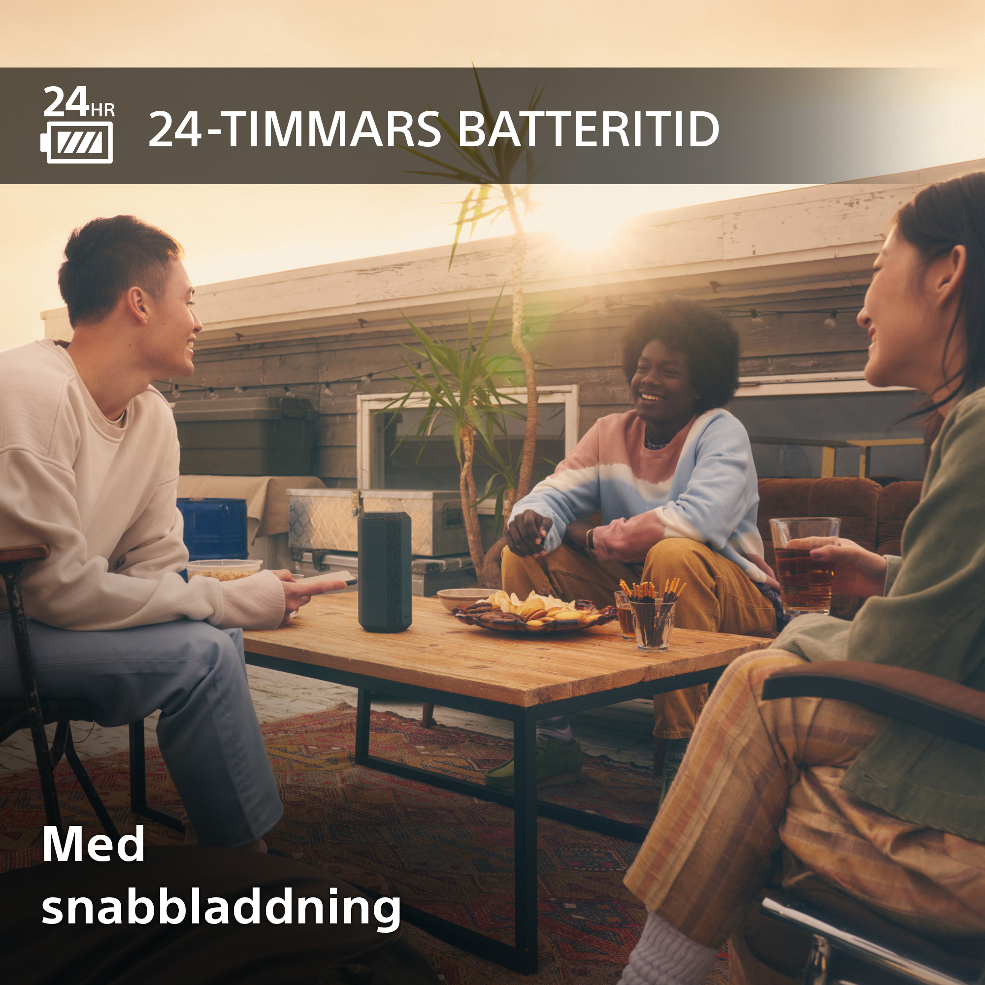 Glada personer på en takterrass med en Sonyhögtalare och snacks på ett bord och svensk text om batteri