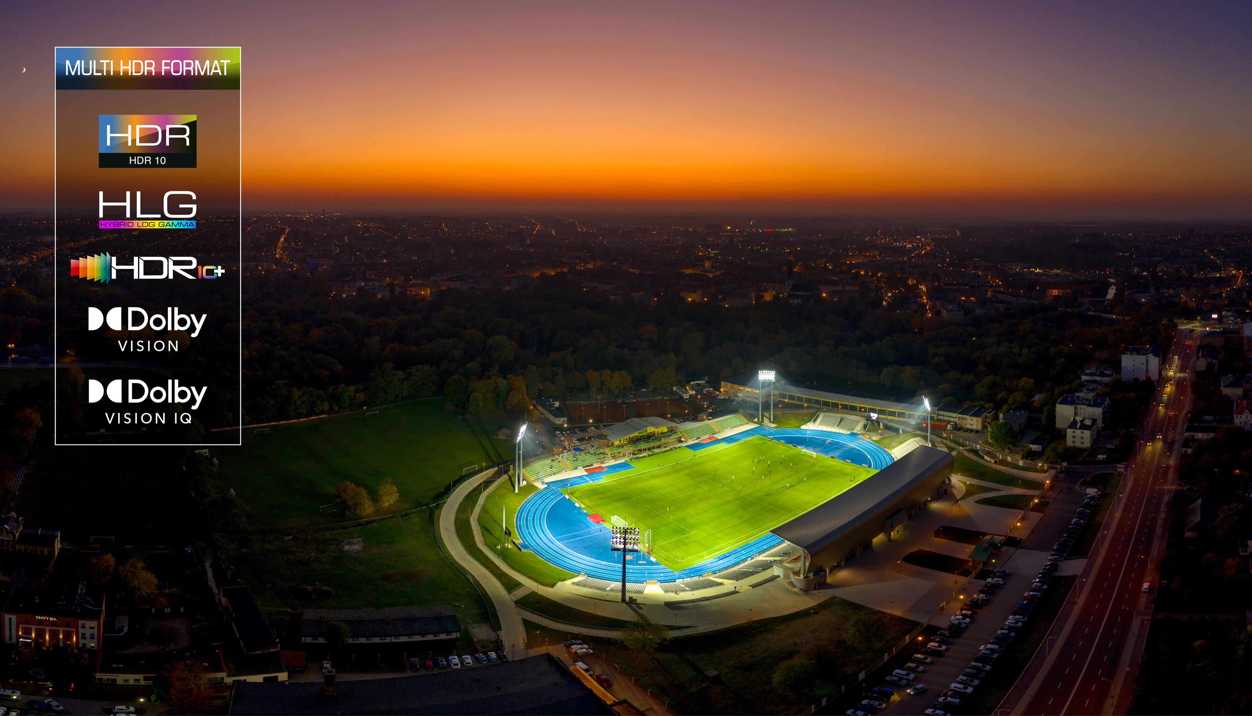 Upplyst fotbollsstadion i en stor stad sett uppifrån med kvällshimmel i bakgrunden med HDR-text i ena hörnet