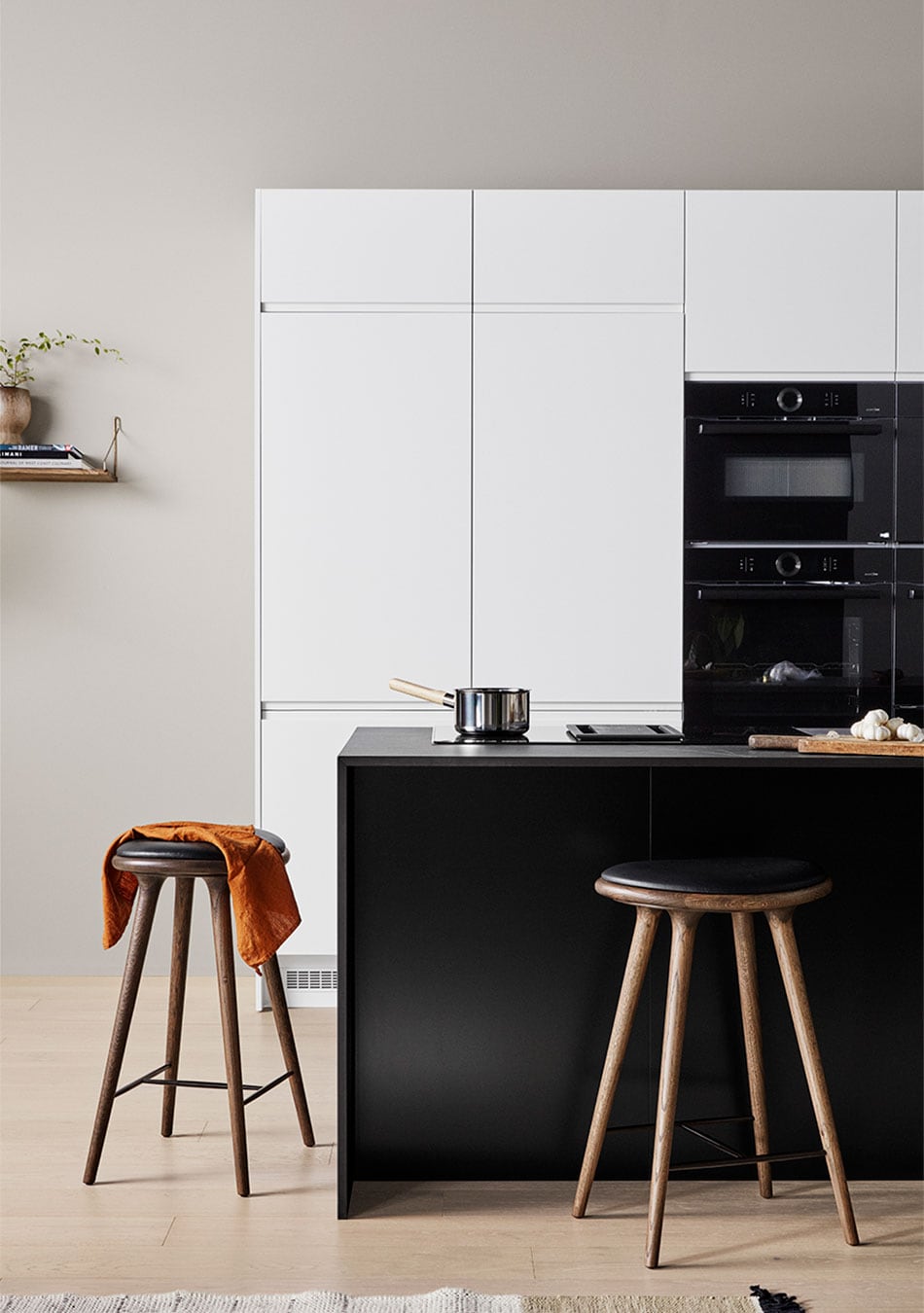 Epoq Pure Matt Black köksö med vita väggskåp, integrerad ugn och kaffemaskin och två barstolar vid köksön