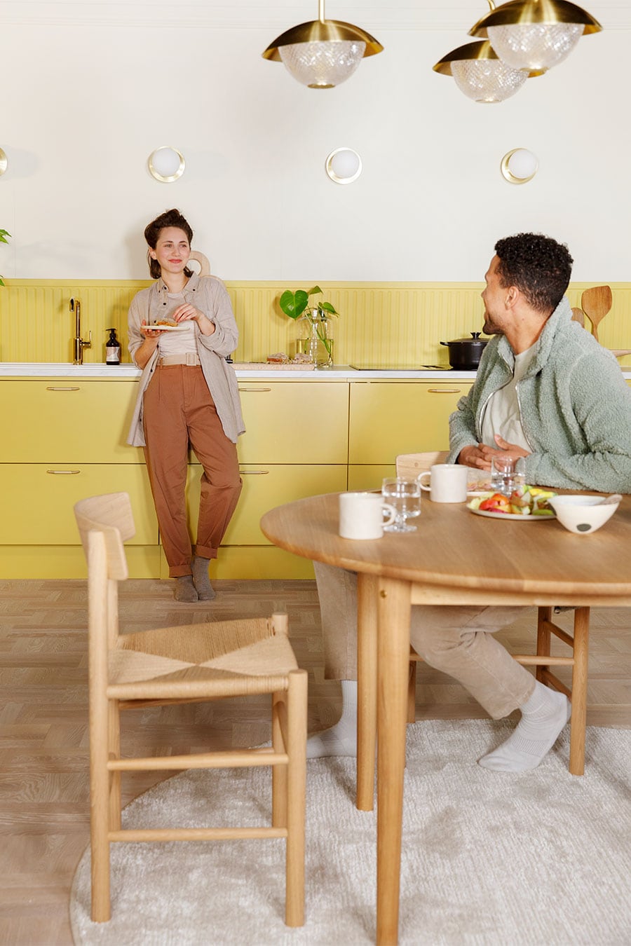 Gult Trend Mellow kök med vit bänkskiva och en kvinna och man som äter frukost.