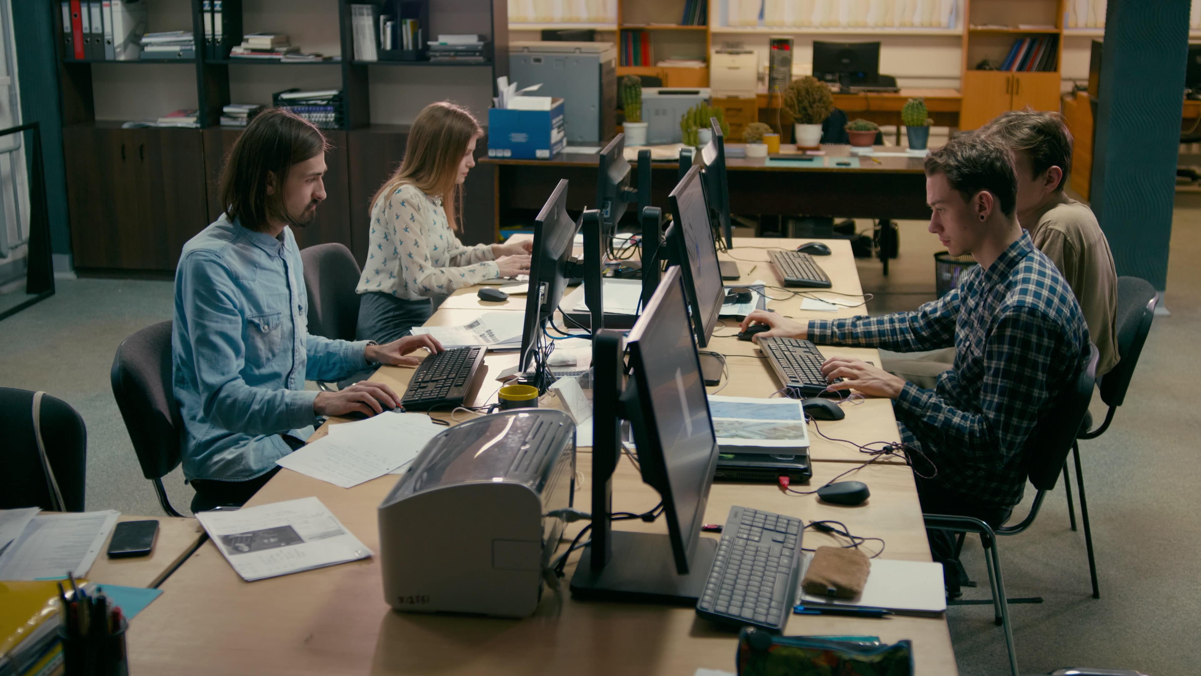Ett team som arbetar vid sina datorer i ett kontor i ett öppet kontorlandskap