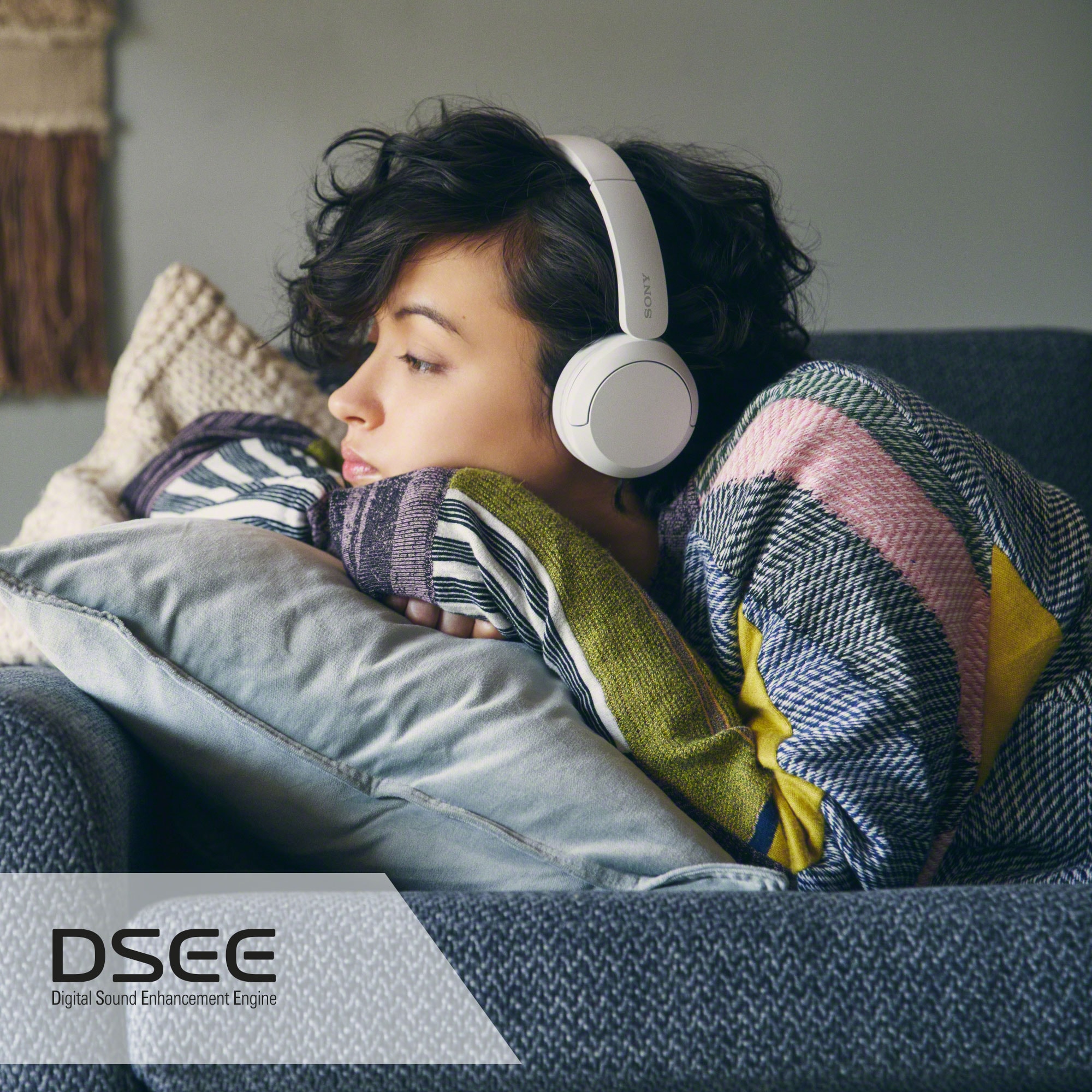 Kvinna i en soffa med WH-CH520-hörlurar och lyssnar på musik