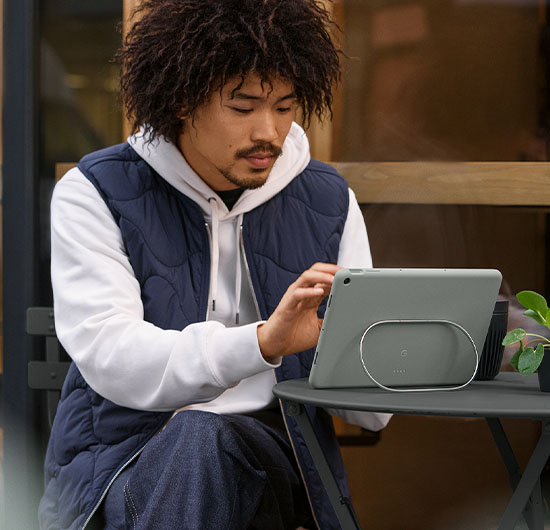 Man som sitter utomhus med Google Pixel Tablet